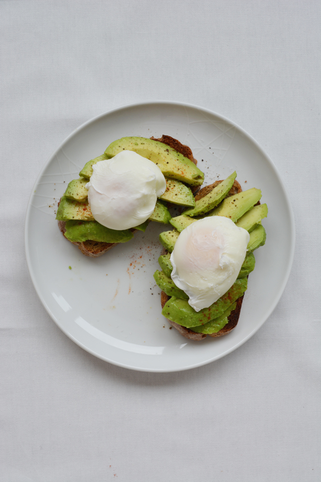 Avocado and poached egg toast on a white plate with a white background taken from the overhead.