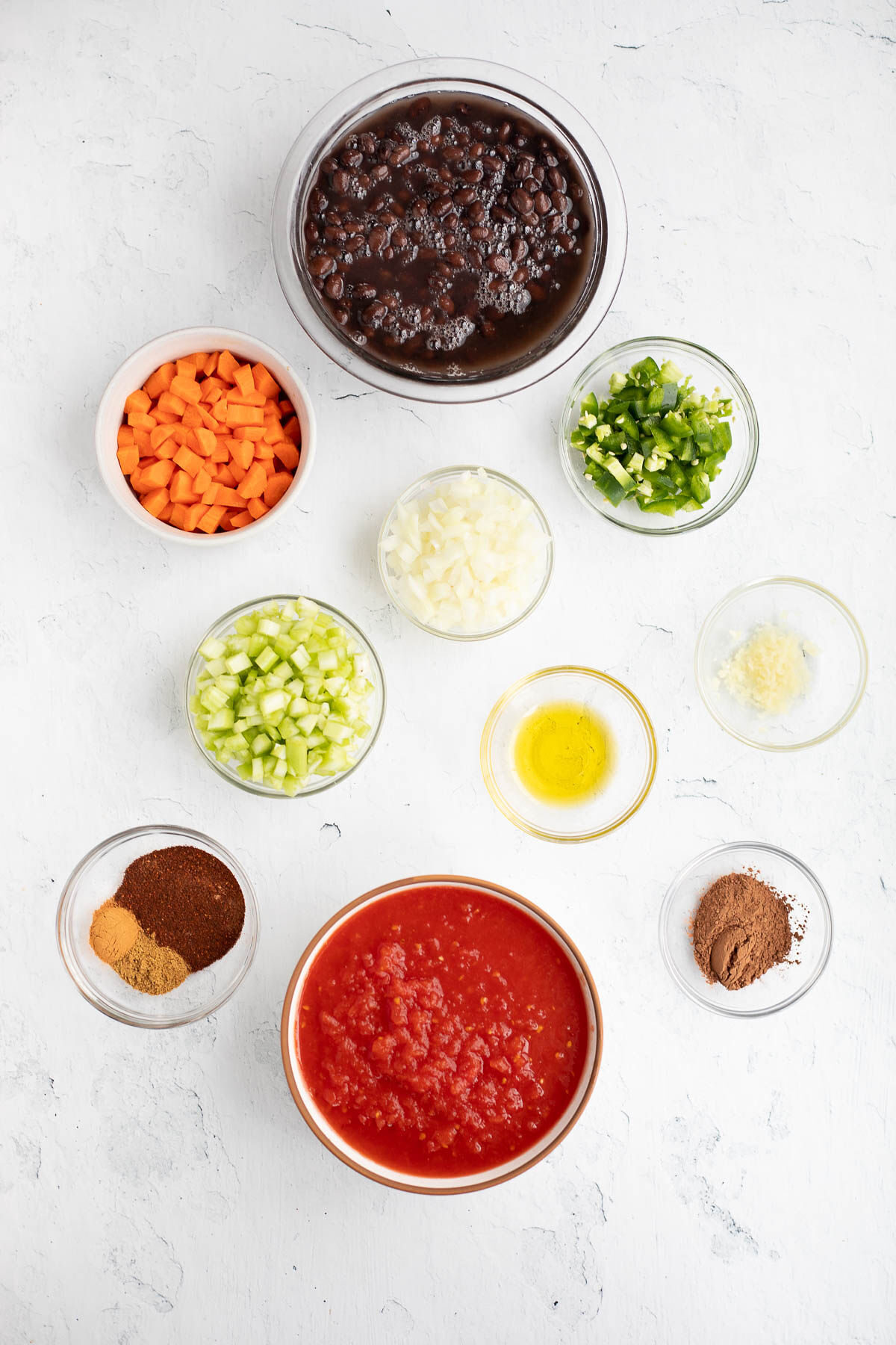 Ingredients for Black Bean Chili with Chocolate in various sized glass bowls, top view.