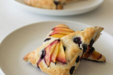 Blueberry and nectarine scones on a stone colored plate with more scones in the background on a white table