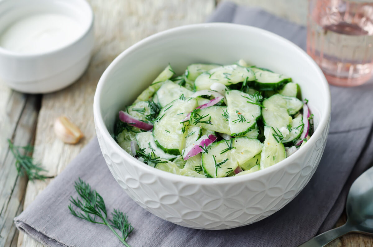 Creamy cucumber salad in a white bowl.