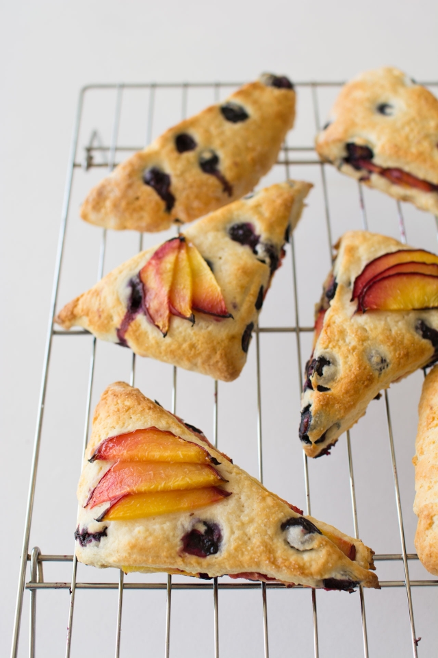 Baked Blueberry and Nectarine Scones on a wire cooling rack with a white background.