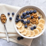 A healthy bowl of oatmeal with bananas, blueberries, and walnuts.