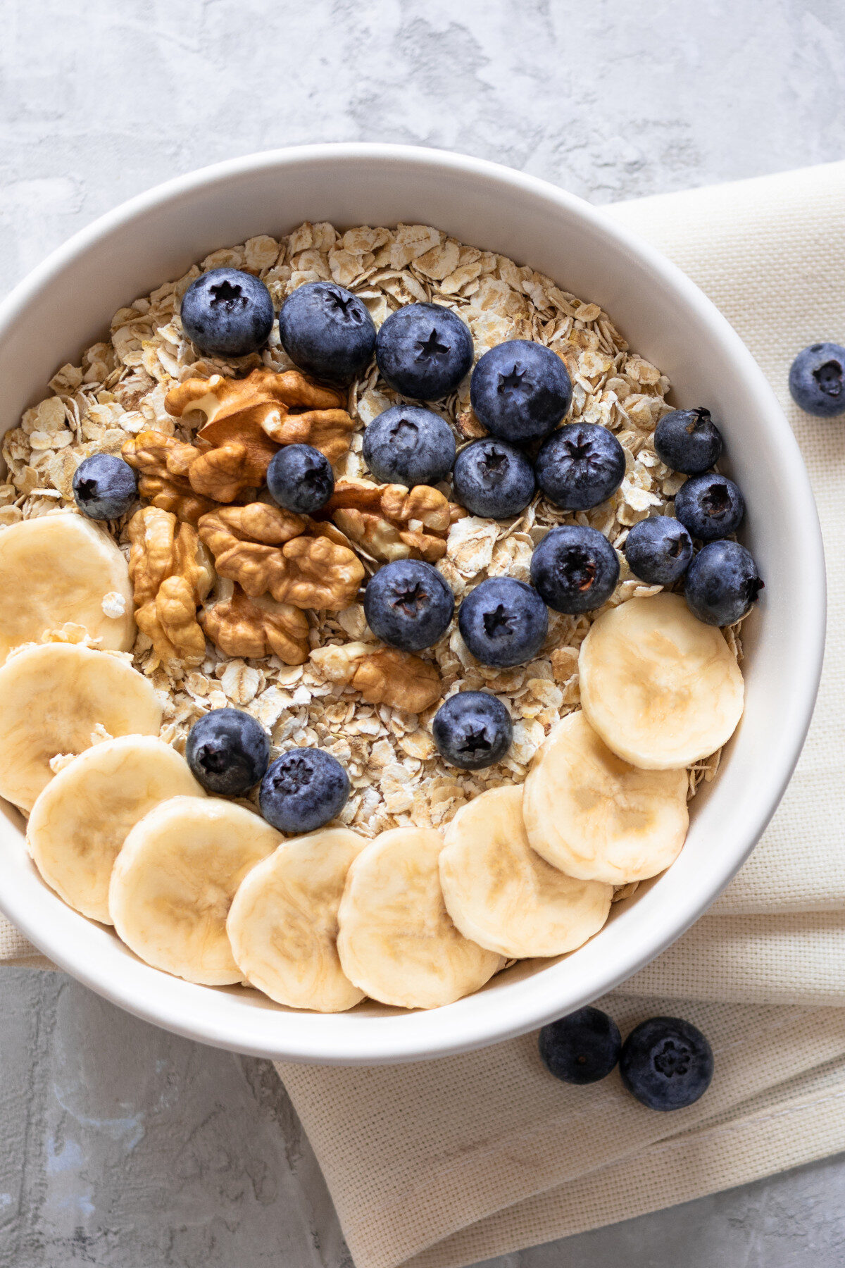A healthy bowl of oatmeal with bananas, blueberries, and walnuts.